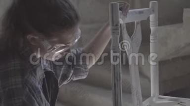 这个女孩在一个木工车间工作，擦家具。